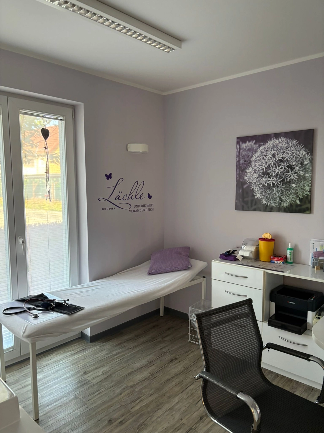 Frauenarztpraxis Dr. A. Dietrich - Gesundheitsdienste für Frauen - Eine Untersuchungsliege mit Stethoskop und lila Kissen in einer kleinen Arztpraxis.